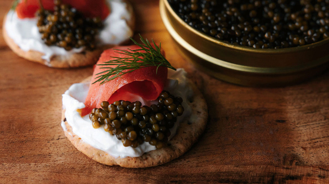 Table with jar of caviar and 2 bllini's with cream cheese, salmon and caviar.