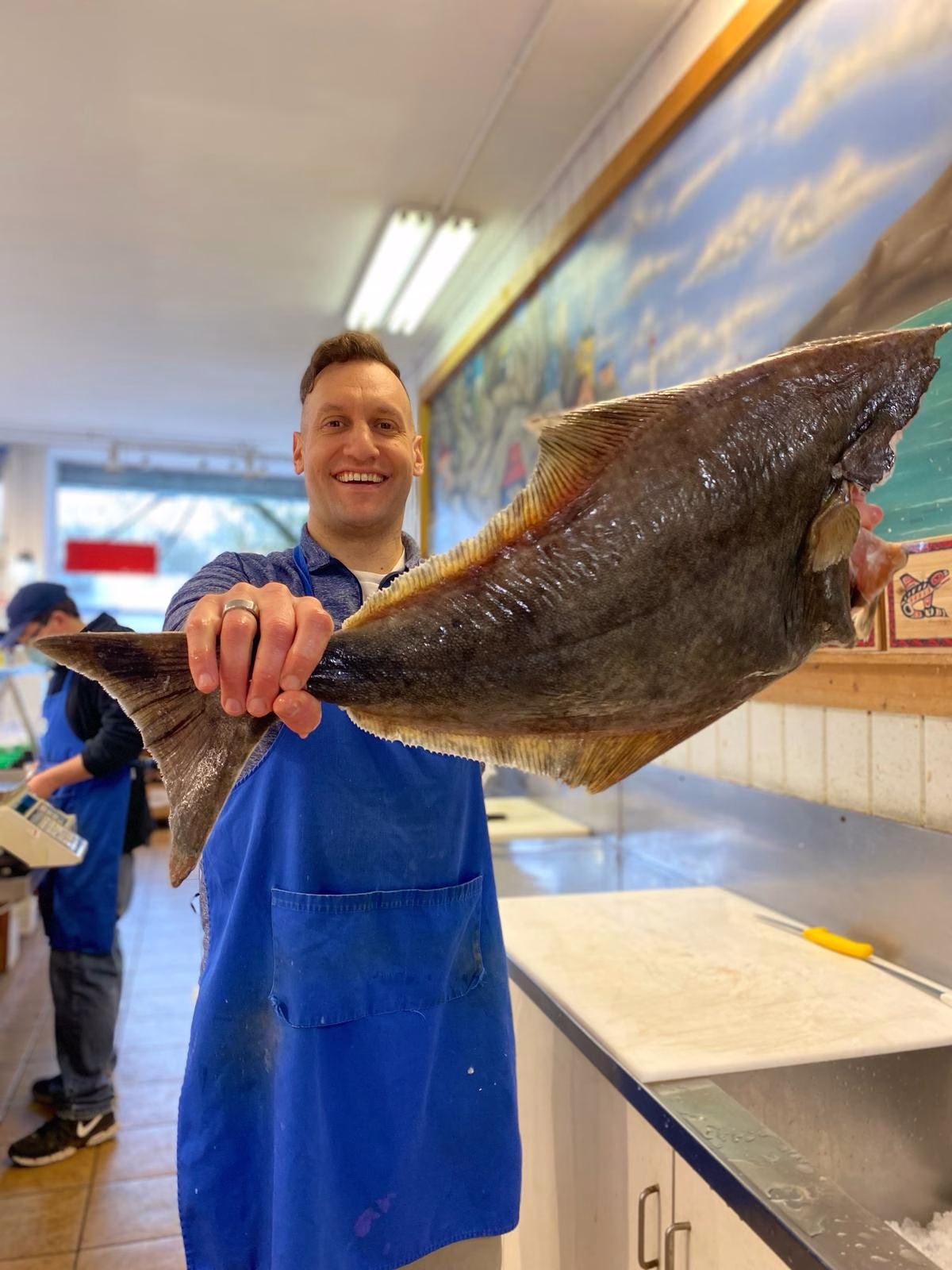 James Heras holding a halibut at 7 Seas Fish Market in Kitsilano, Vancouver