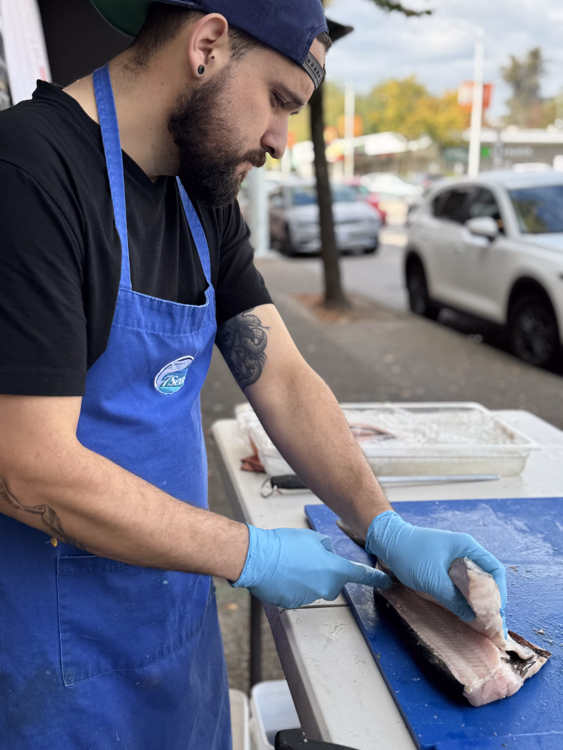 A 7 Seas fishmonger filleting salmon outside the shop